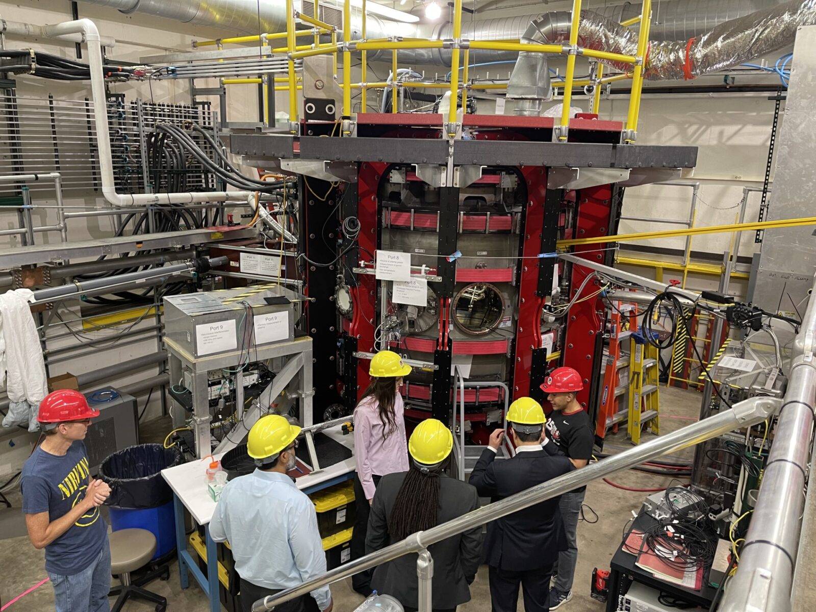 Group of people wearing construction hats in the UW–Madison Pegasus Toroidal Experiment lab.